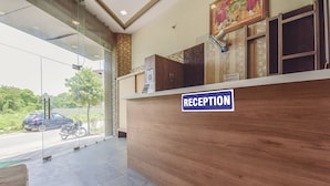 A reception desk with a sign labeled "RECEPTION" and a view of a street with a motorcycle. - Hotel Shivansh (Jaipur)