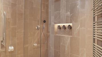 A walk-in shower with a glass door, marble tiles, a towel rack, and a hand dryer.