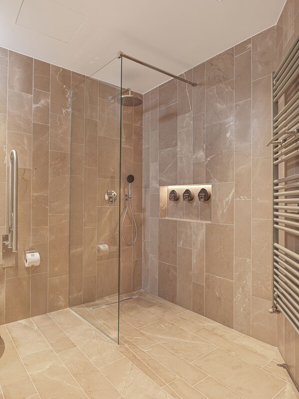 A walk-in shower with a glass door, marble tiles, a towel rack, and a hand dryer. - Pendeli Resort (Platres)