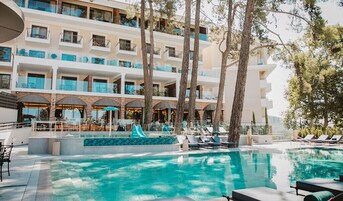 Un hotel con piscina, sillas de descanso y un tobogán.