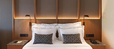 A hotel room with a large bed, two bedside tables, a telephone, and a wall-mounted lamp.
