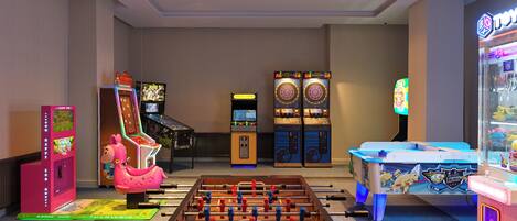 A room with a foosball table, arcade games, and a claw machine.