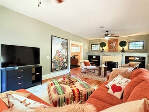 A living room with a television, sofa, ottoman, and fireplace.