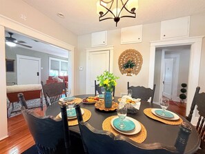 A dining room with a dark wooden table set for four, surrounded by chairs. - Stylish Abilene Home - Berry Suites (Abilene)
