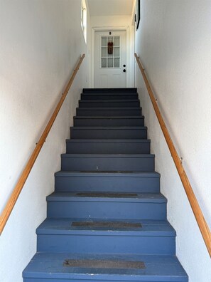 A staircase with wooden handrails leading to a white door marked with the letter 'B'.