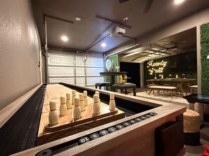 A foosball table in a room with a green wall and a neon sign. - Howdy Y’all Ranch | Luxe Western Retreat (Abilene)
