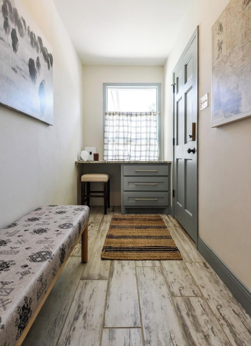 A narrow hallway with a bench, a desk, and a wardrobe.