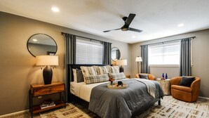 A bedroom with a bed, bedside tables, a chair, a ceiling fan, and a window with curtains. - Howdy Y’all Ranch | Luxe Western Retreat (Abilene)