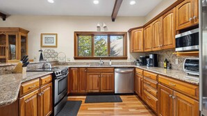 A kitchen with wooden cabinets, granite countertops, a stainless steel oven, and a dishwasher.