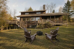 A wooden cabin with a deck, outdoor seating, and a chimney.
