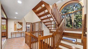 A wooden staircase with a view of trees outside, a tiled floor, and a window with a view.
