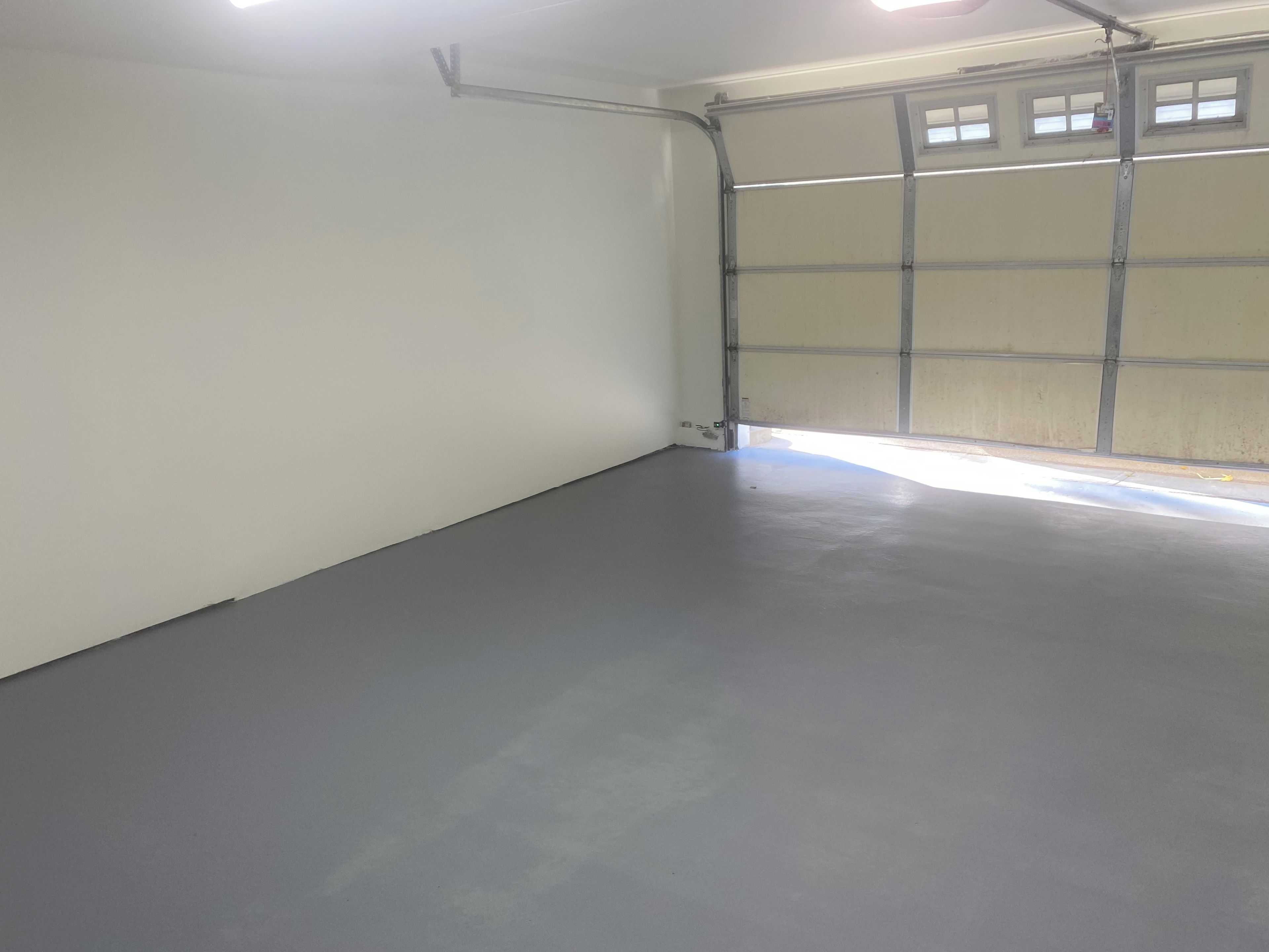 A garage with a concrete floor, a metal garage door, and a light fixture on the ceiling.