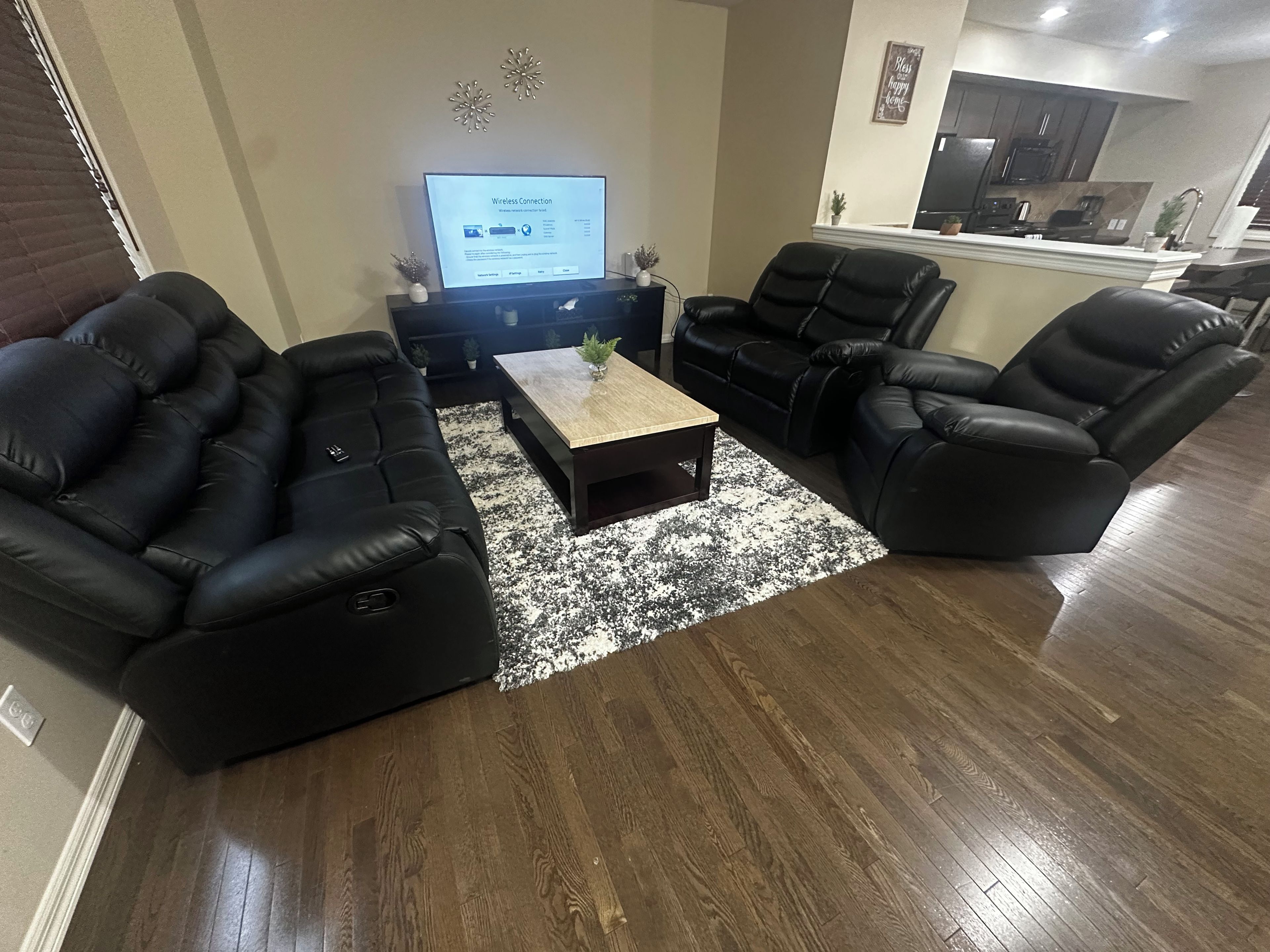 A living room with a sectional sofa, a coffee table, and a television displaying a wireless connection screen.