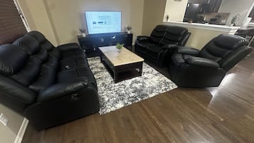 A living room with a sectional sofa, a coffee table, and a television displaying a wireless connection screen.