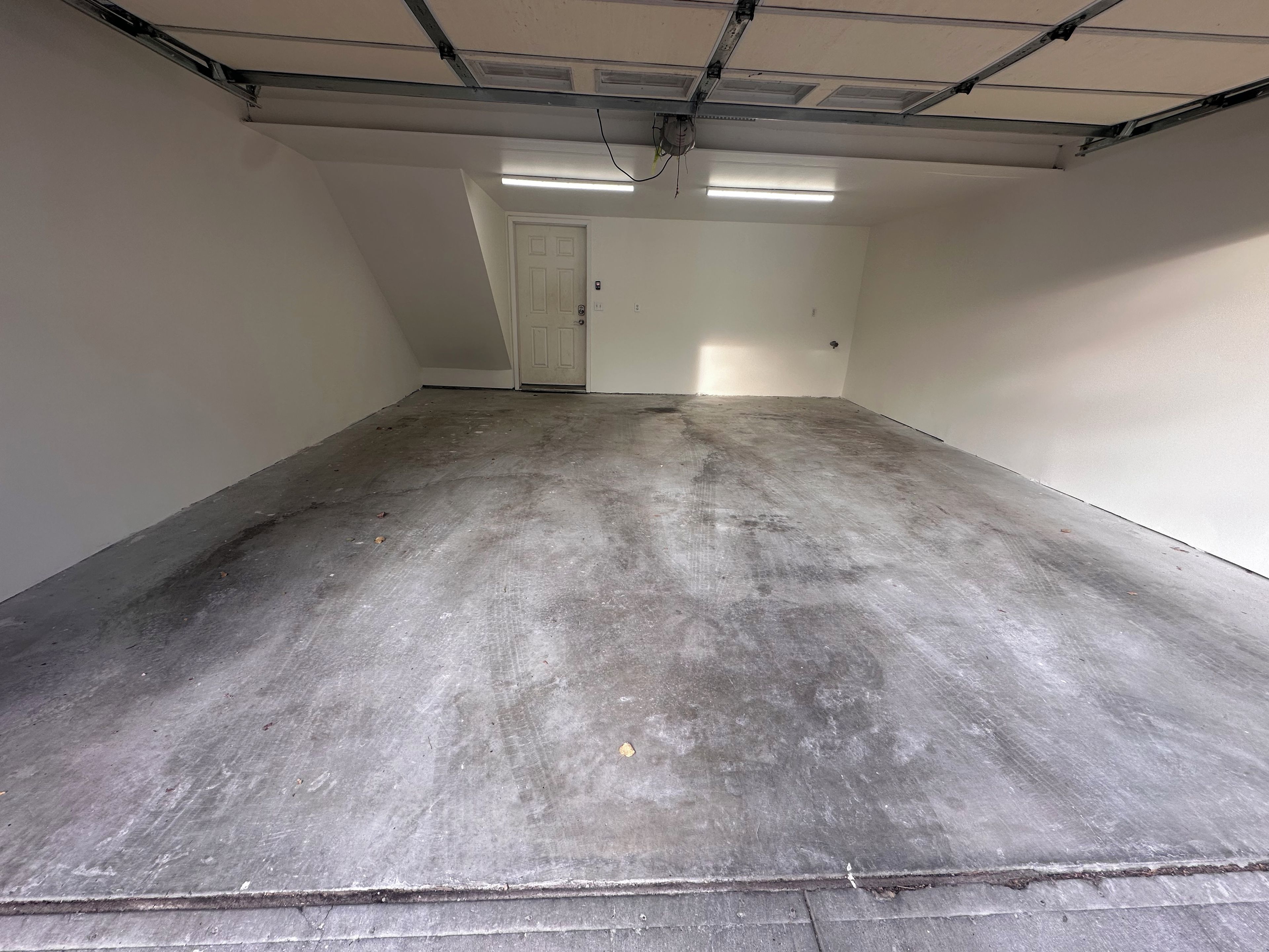 A clean, empty room with a concrete floor, white walls, and a door leading to another space.