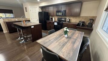 Una cocina moderna con gabinetes de madera oscura, una isla central con taburetes de bar, un microondas, estufa y cafetera.