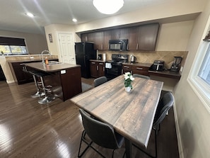 Una cocina moderna con gabinetes de madera oscura, una isla central con taburetes de bar, un microondas, estufa y cafetera.