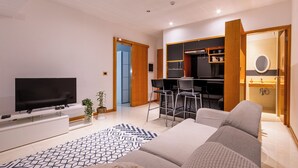 Ett modernt vardagsrum med en platt-TV, en soffa, ett soffbord och en mönstrad matta.