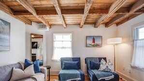 A living room with wooden beams, a sofa set, a side table, a lamp, and a painting of a lighthouse. - **New Listing for 2026** Classic Downtown Historic Lewes Home two blocks to Second Street and only 4minutes to the Beach (Lewes)
