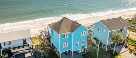 Una propiedad costera con dos casas azules, un edificio blanco y vista al mar.