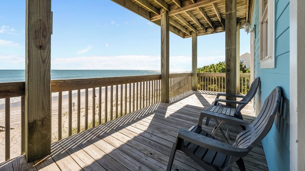 Eine Holzdar Terrasse mit Blick auf den Strand und das Meer.