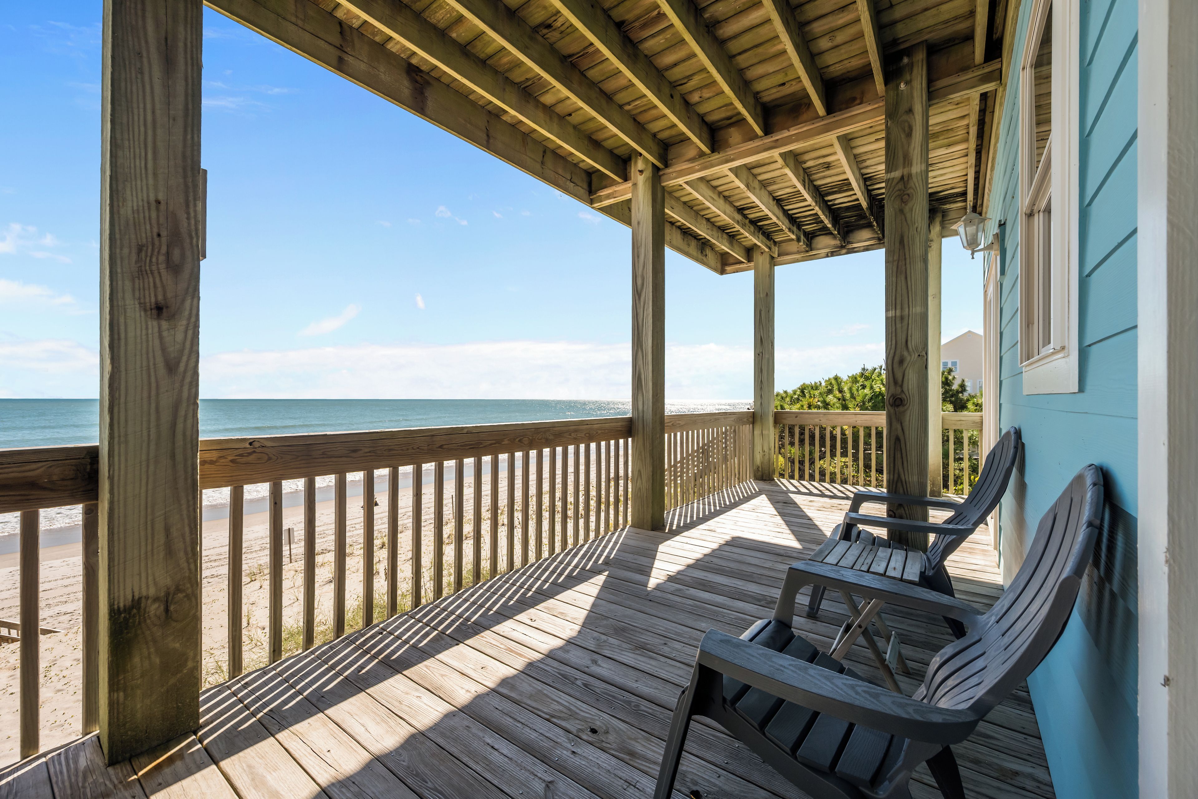 A wooden deck with a view of the beach and ocean.