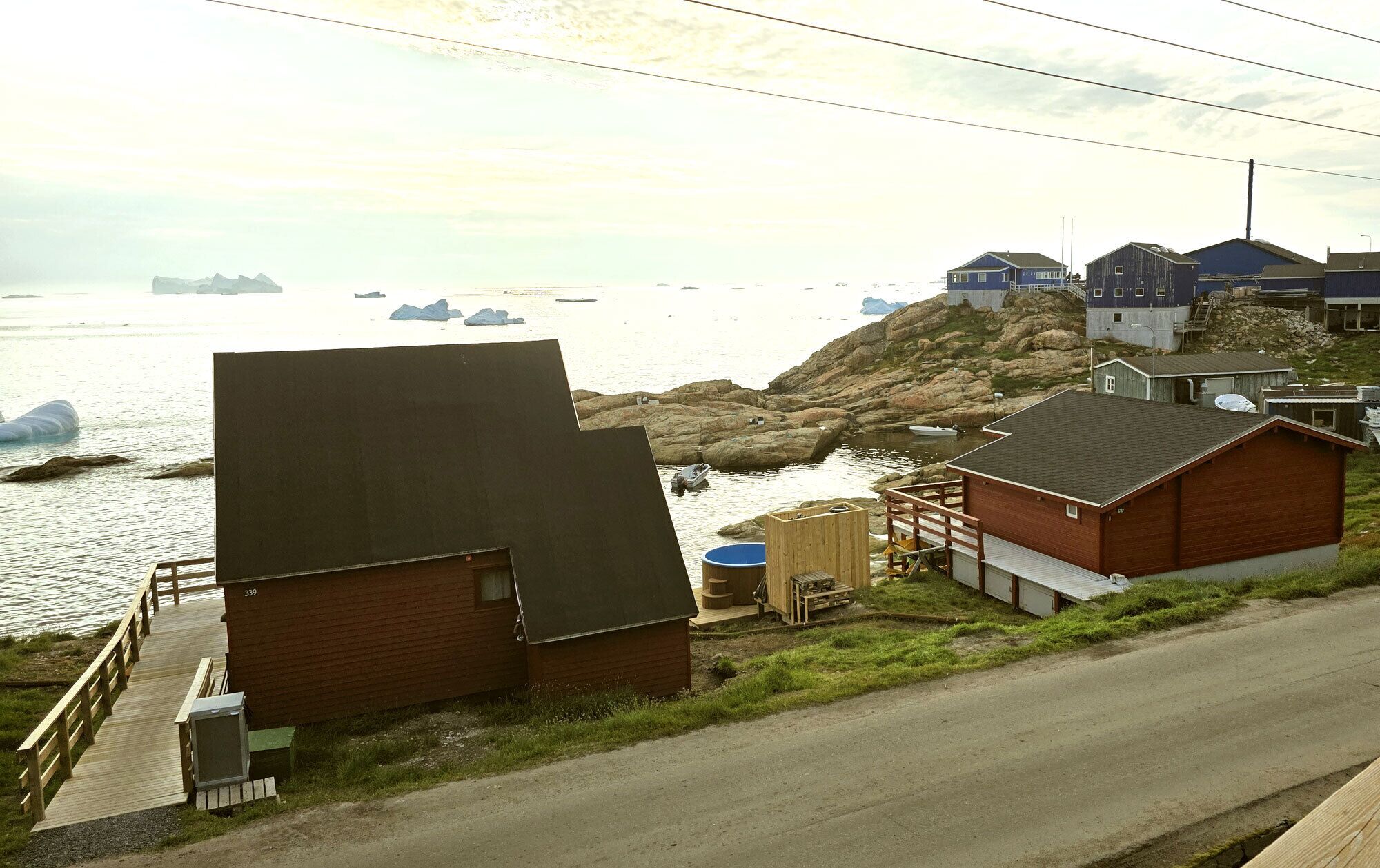 A coastal building with a dock, a large water tank, and a rocky shoreline.