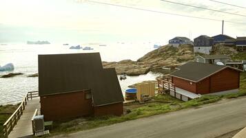A coastal building with a dock, a large water tank, and a rocky shoreline.