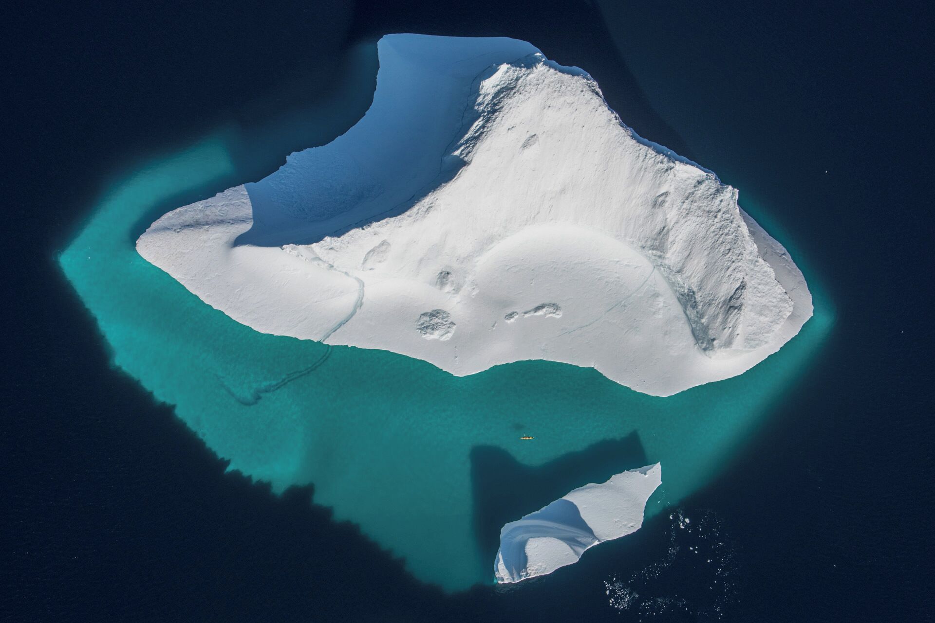 An aerial view of a large, isolated island with clear turquoise waters surrounding it.