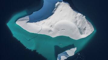An aerial view of a large, isolated island with clear turquoise waters surrounding it.