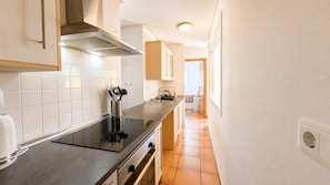 A kitchen with white cabinets, a black induction cooktop, and a tiled backsplash. - Villa Alegre, Mar Menor Golf (Torre-Pacheco)