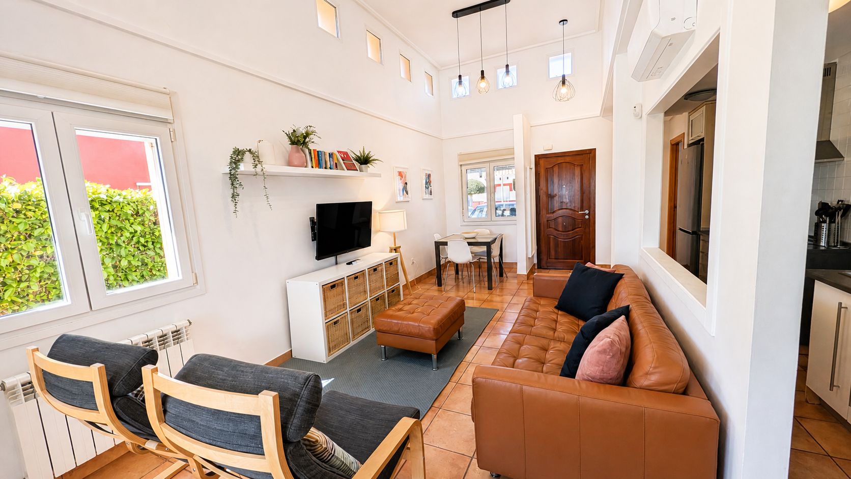 Uma sala de estar moderna com sofá, cadeiras, televisão e área de jantar.