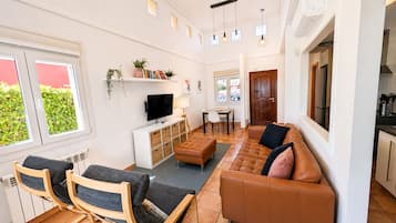 A modern living room with a sofa, chairs, a TV, and a dining area.