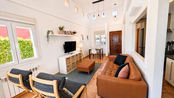 Una sala moderna con sofá, sillones, televisor y comedor.