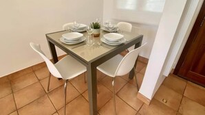 A dining area with a square table, four chairs, and a potted plant.