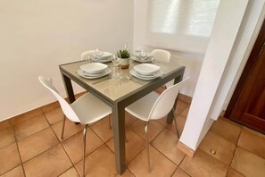 A dining area with a square table, four chairs, and a potted plant. - Villa Alegre, Mar Menor Golf (Torre-Pacheco)