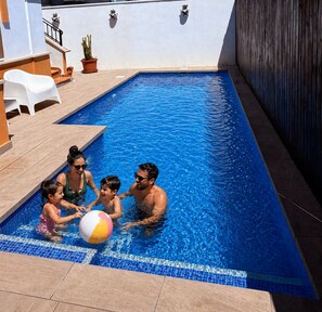 A swimming pool with a tiled edge, a white chair, and a potted plant. - Villa Alegre, Mar Menor Golf (Torre-Pacheco)
