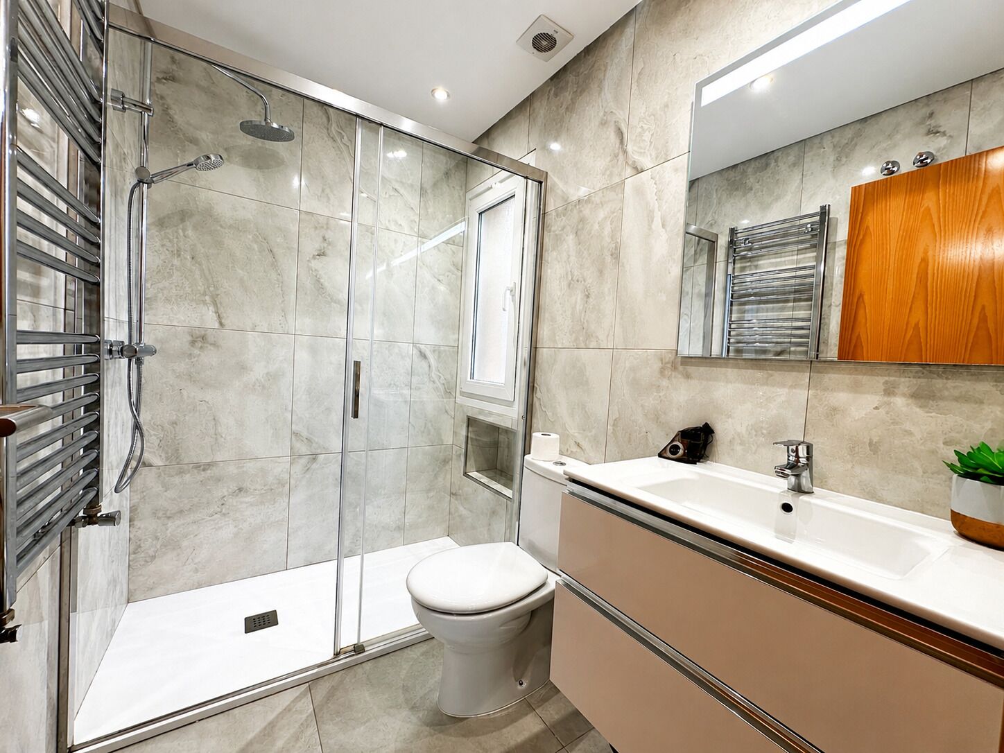 A modern bathroom with a glass-enclosed shower, a toilet, and a vanity with a mirror and sink.
