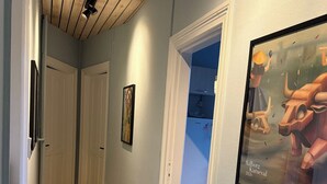Un passadís amb terres de fusta, portes blanques i una obra d'art amb marc a la paret.