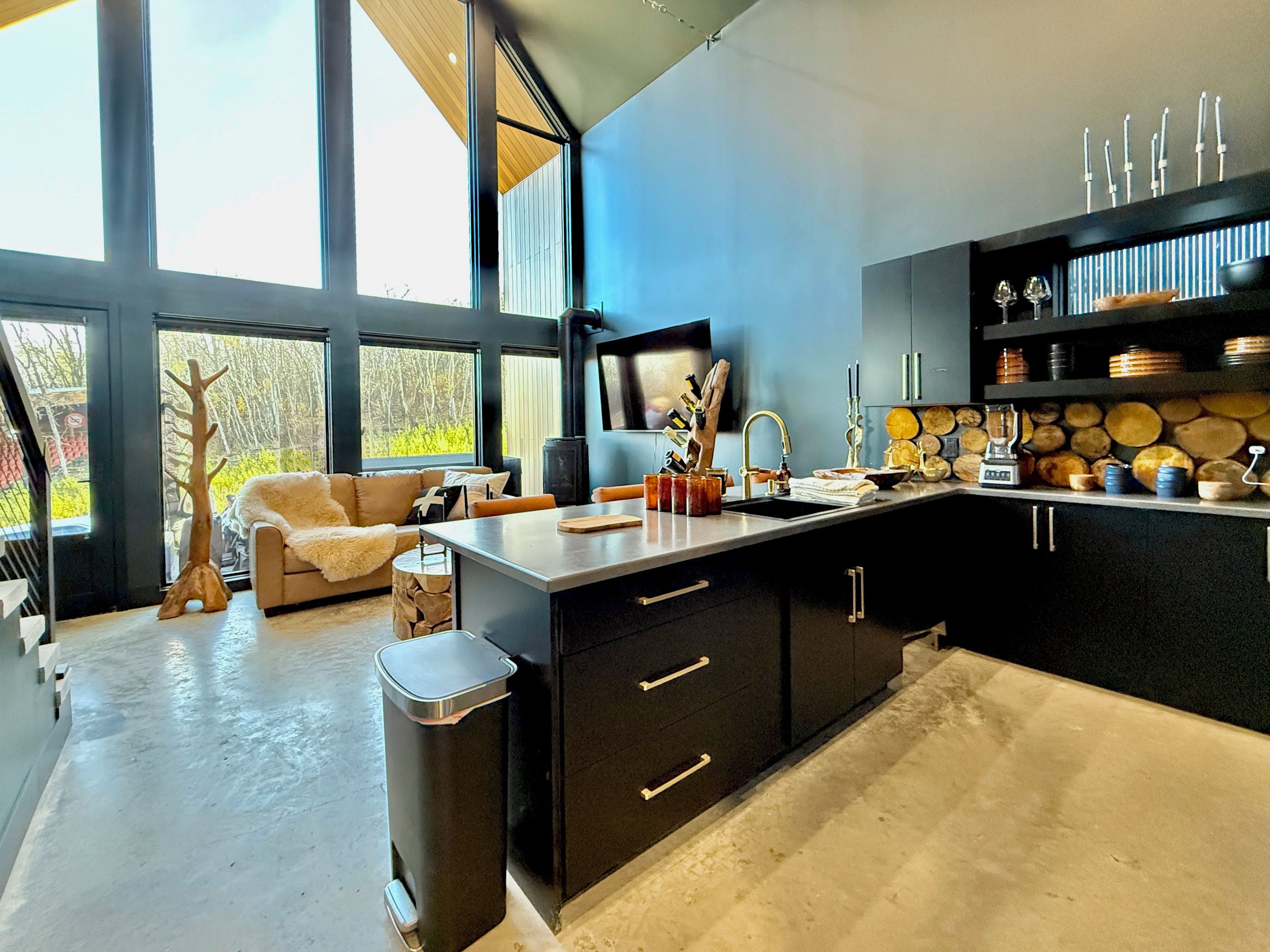 A modern kitchen with a large window, a built-in stove, and a dining area with a sofa.
