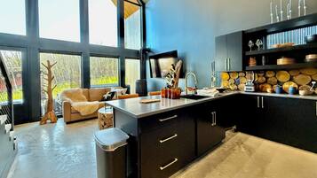 A modern kitchen with a large window, a built-in stove, and a dining area with a sofa.