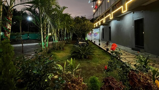 A courtyard with potted plants and a building with illuminated railings. - Hotel Golden Galaxy (Mahabaleshwar)