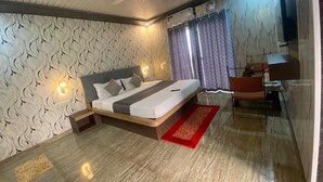 A modern bedroom with a bed, a desk, and a TV. - Hotel Golden Galaxy (Mahabaleshwar)