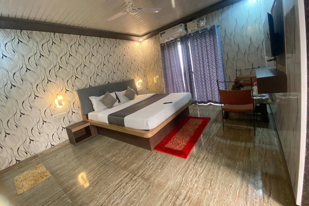 A modern bedroom with a bed, a desk, and a TV.