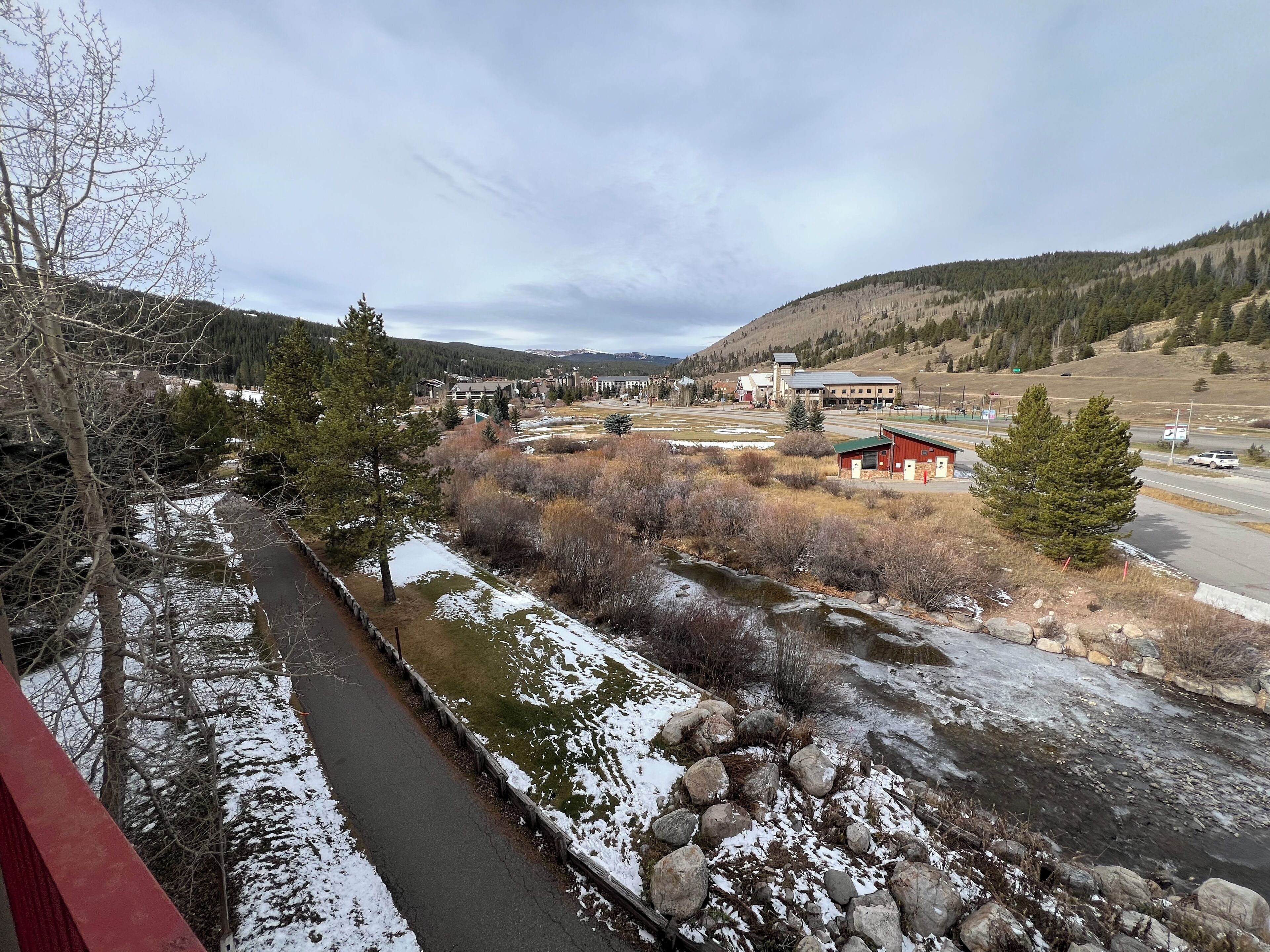 A riverside view of a town with buildings, a bridge, and a mountainous backdrop.