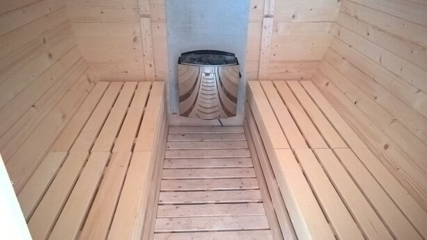 Een houten sauna met een bank en een centrale verwarming.
