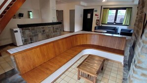 Een modern interieur met een gebogen houten bank, een stenen openhaard, een keukenhoek en een trap.