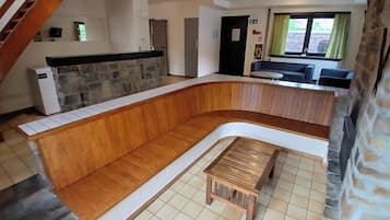 Een modern interieur met een gebogen houten bank, een stenen openhaard, een keukenhoek en een trap.