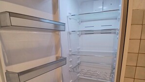 Een interieur van een moderne, lege koelkast met meerdere planken en lades.