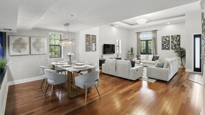 Uma sala de estar ampla, com área de refeições, piso de madeira e móveis modernos.